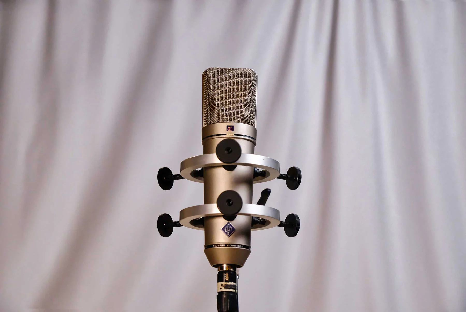 白いバックドロップの前に正面から設置されたNeumann U87マイク。